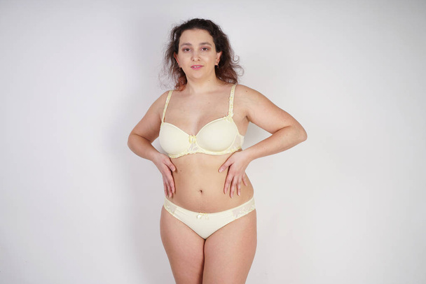 Stüdyo beyaz arka planda sarı iç çamaşırı poz artı boyutu vücut ile kadınsı kadın - Fotoğraf, Görsel