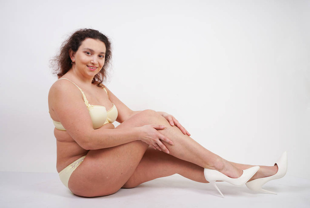 Mujer femenina con cuerpo de talla grande en lencería amarilla posando sobre fondo blanco en Studio
 - Foto, imagen