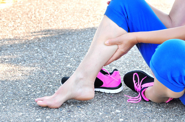 Uszkodzenie mięśni. Running urazy nogi wypadek-Sport kobieta biegacz boli trzymając bolesną nogę. Sportowiec kobieta ma uszkodzenia mięśni, skręconą nogę podczas treningu w przyrodzie. - Zdjęcie, obraz