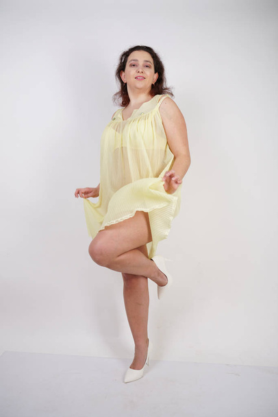 pretty chubby girl wearing fashionable yellow underwear and loves her body and herself. plump woman in lingerie on white background. - Photo, Image