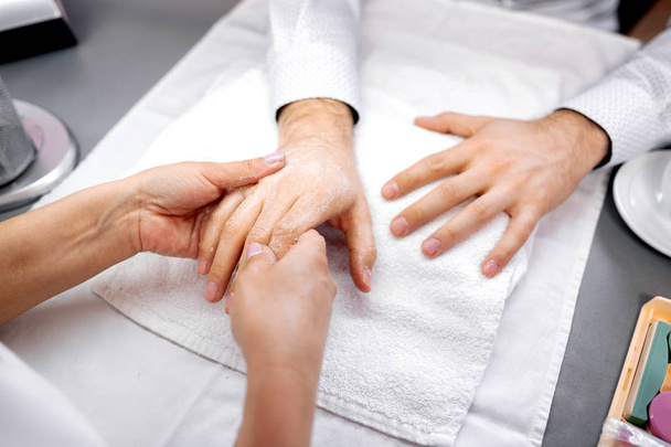 Manicurist holding a hand of a man for further treatment - Foto, imagen