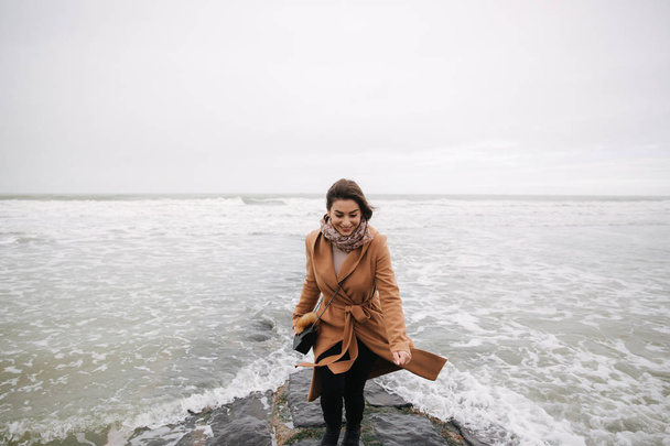 Woman running away from the waves of North Sea. Female afraid to be wet in cold weather - Foto, immagini