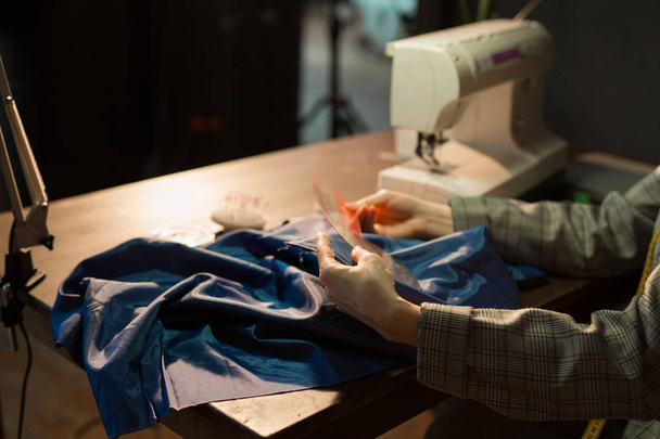 woman seamstress tailor embroider dress behind sewing machine at work - Foto, Bild