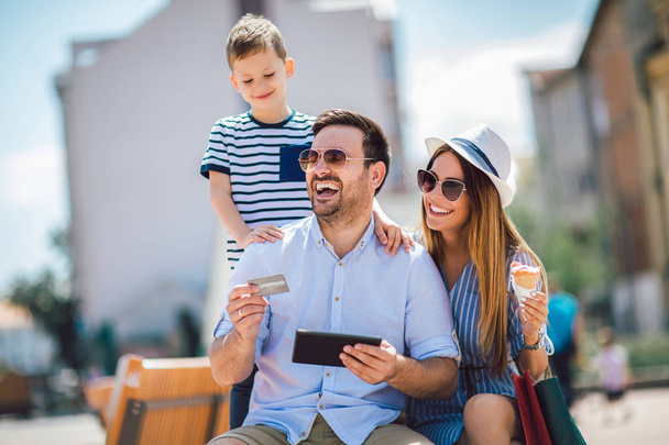 Sonrientes padres y niño pequeño con tableta PC y tarjeta de crédito ou
 - Foto, imagen