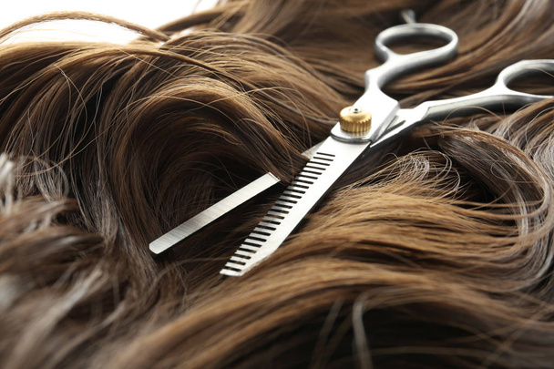 Thinning scissors on brown wavy hair, closeup. Hairdresser service - Φωτογραφία, εικόνα