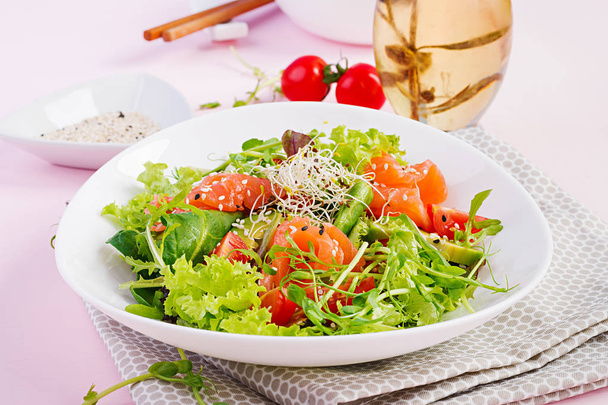 Diet menu. Healthy salad of fresh vegetables - tomatoes, avocado, arugula, seeds and salmon on a bowl. Vegan food. - Foto, imagen