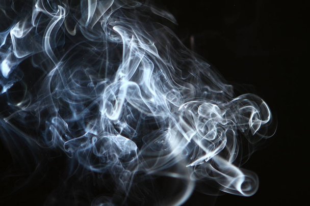 pretty flowing light blue smoke on the heavy black background. - Photo, image
