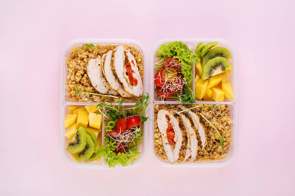 Lunchbox Huhn, Bulgur, Mikrogemüse, Tomaten und Obst. gesunde Fitnesskost. Mitnehmen. Lunchbox. Ansicht von oben - Foto, Bild
