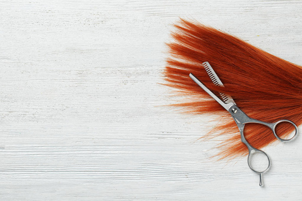 白い木製の背景にテキストのための赤い髪、薄いはさみとスペースを持つフラットレイコンポジション。美容院サービス - 写真・画像