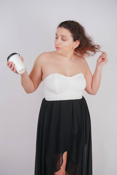 emotivo plus size donna con tazza di tè di carta nelle sue mani su sfondo bianco
 - Foto, immagini