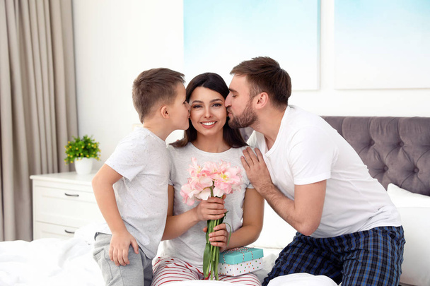 Father and son congratulating mom in bedroom. Happy Mother's Day - Фото, изображение