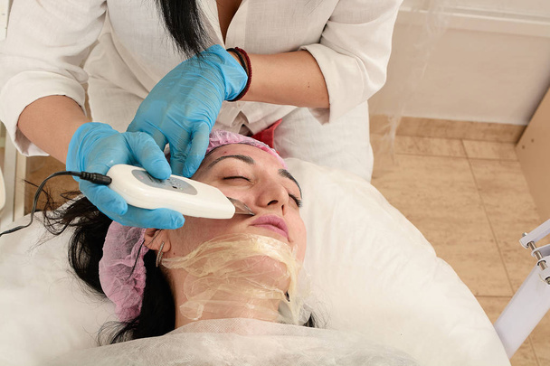 Młoda kobieta w salonie piękności robi peeling ultradźwiękowy i zabieg oczyszczania twarzy. - Zdjęcie, obraz