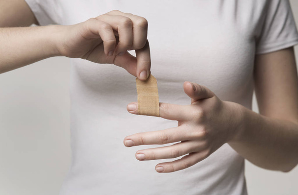 Woman using adhesive tape on injured finger - Zdjęcie, obraz
