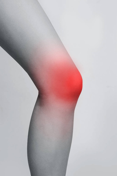 Female leg with red zone of injured knee - Fotó, kép