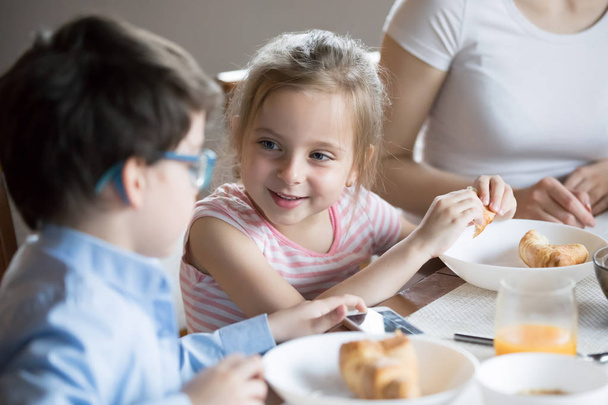 Smiling little girl talking with brother at breakfast at home - Foto, Bild