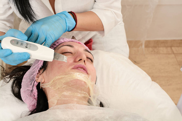 Jonge vrouw in schoonheidssalon doen echografie peeling en gezichtsreiniging procedure. - Foto, afbeelding