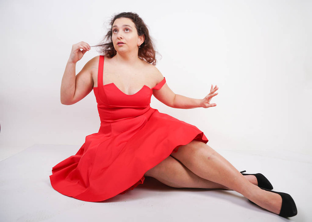 plump woman in a red pinup dress. chubby fashionable girl standing on white background in Studio - Φωτογραφία, εικόνα