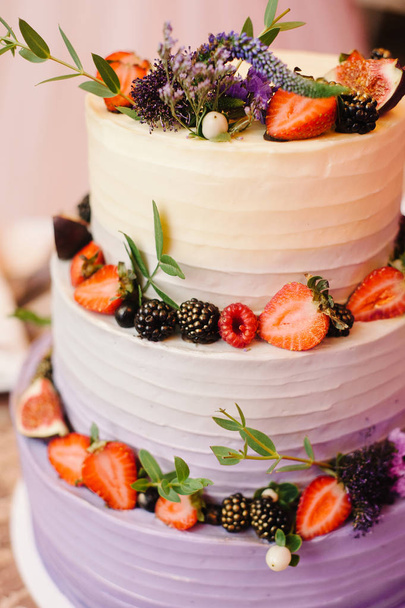 Bright three tiered wedding cake. White creamy cake decorated with fesh fruits, berries and flowers. - Φωτογραφία, εικόνα