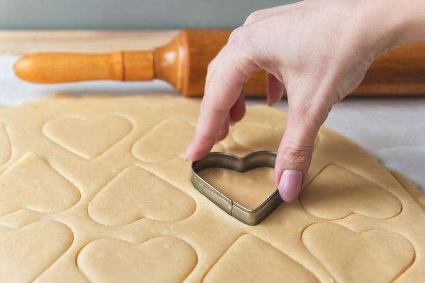 Het proces van het bakken van cookies thuis. Deeg voor koekjes. Hartvormige cookie cutters snijden vakantie suiker koekjes. St. valentines dag. Zijaanzicht - Foto, afbeelding