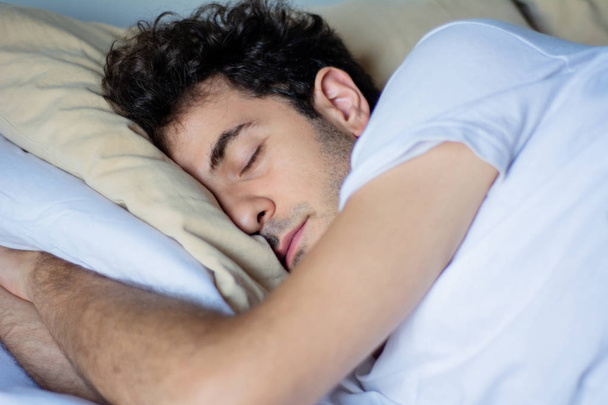 Young man sleeping in bed - Fotó, kép