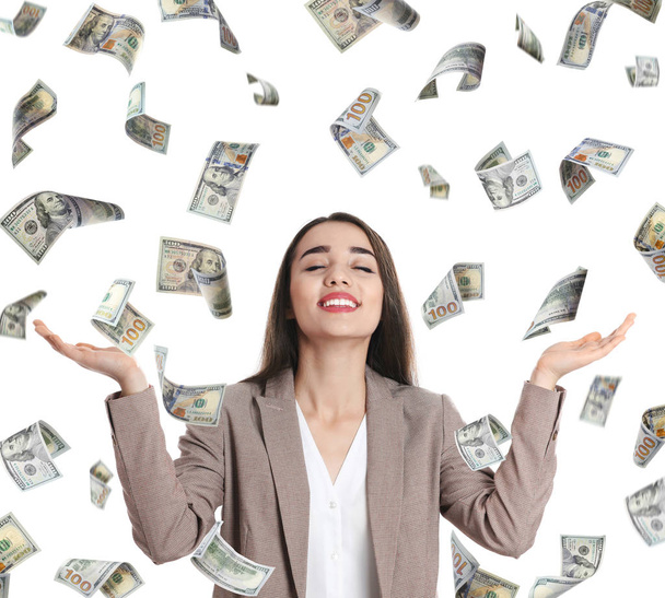 Happy young businesswoman under rain of money on white background - Photo, Image