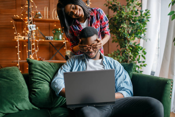 Black couple with laptop having fun on sofa at home. Happy african love couple leisures in their house, cheerful family relaxing in living room - Photo, Image