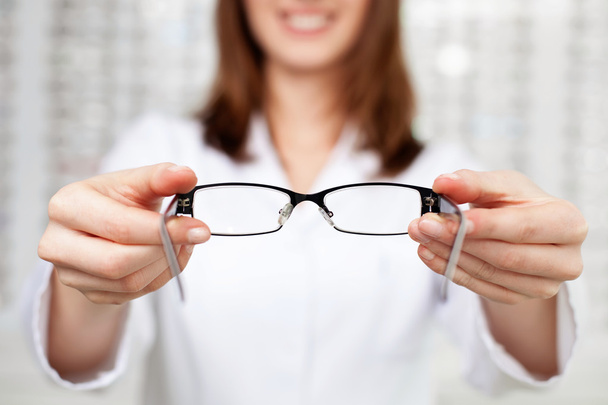 optometrist, optician giving glasses to try - Foto, imagen