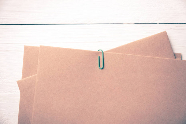 brown paper with green paper clip over white table vintage style - Foto, afbeelding