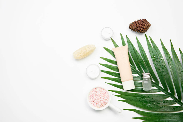 化粧品のクリームのボトル、空白のラベル パッケージと緑の葉の背景に成分のモックアップ。自然化粧品のコンセプト. - 写真・画像