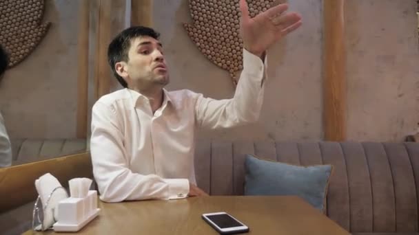 disgruntled cafe guest uses beckoning gesture to call waiter and makes face on couch at mirror and table in pizzeria - Кадри, відео