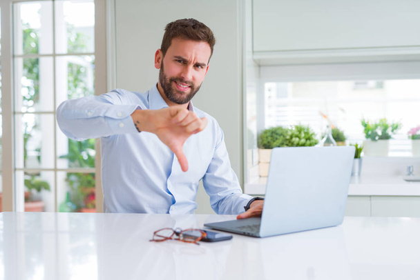 Handsome business man working using computer laptop with angry face, negative sign showing dislike with thumbs down, rejection concept - 写真・画像