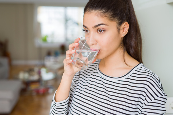Όμορφη νεαρή γυναίκα πίνοντας ένα φρέσκο ποτήρι νερό στο σπίτι - Φωτογραφία, εικόνα