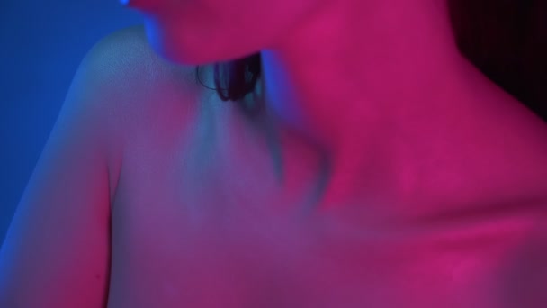 青とピンクのネオンライトに立つモデルの顔に鎖骨からクローズアップ撮影注意深く上向きに見える. - 映像、動画