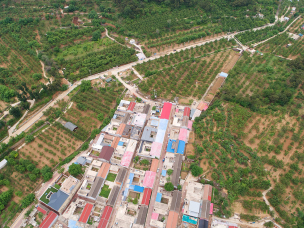 Вид с воздуха на маленькую деревню с небольшим внутренним двориком и домом в фермерском стиле в загородном районе Хуайхэ рядом с горой, Китай
 - Фото, изображение