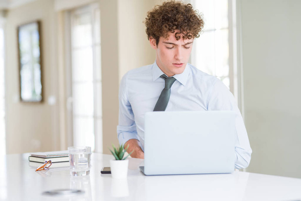 Молодой бизнесмен, работающий с ноутбуком в офисе с рукой на животе, потому что тошнота, болезненное заболевание чувствуют себя нездоровыми. Концепция Ache
. - Фото, изображение