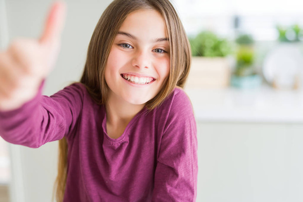 Beautiful young girl kid doing happy thumbs up gesture with hand. Approving expression looking at the camera showing success. - Foto, Bild