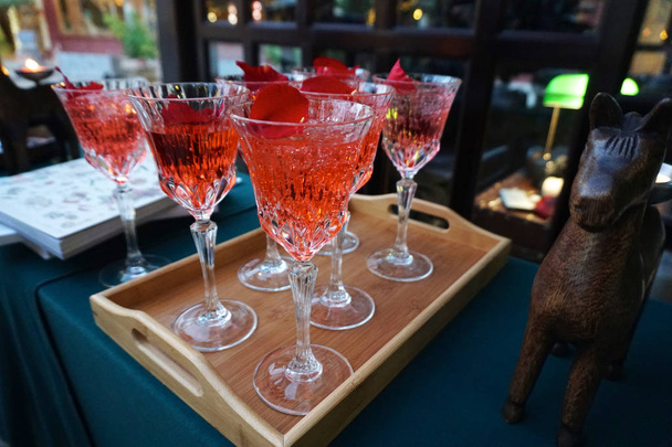 Cocktail rouge dans des verres de fantaisie sur assiette en bois et table au restaurant
 - Photo, image