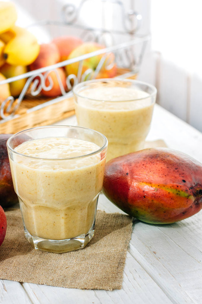 Glas met verse Mango smoothie over witte houten tafel - Foto, afbeelding