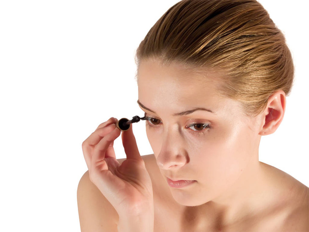 young woman putting make up on her face. Isolated - Photo, Image