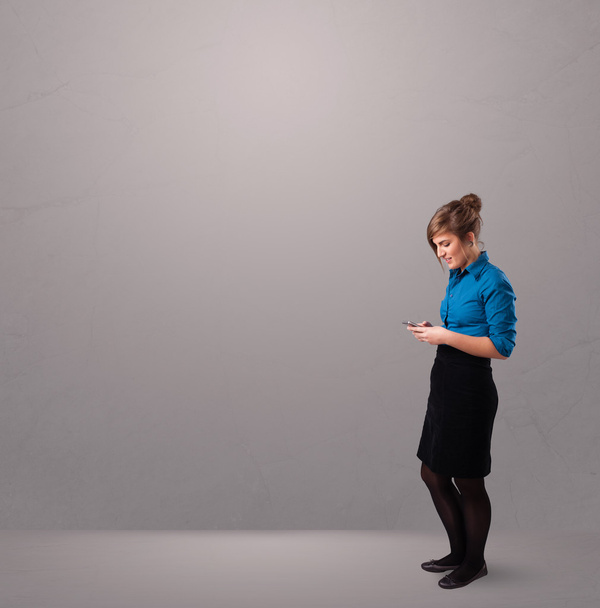 young lady standing and holding a phone with copy space - Foto, afbeelding