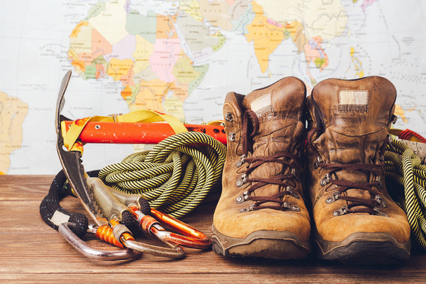Equipment for high-altitude climbing: boots, sport ropes, carbines on the background of a geographical map. Copy space - Photo, Image