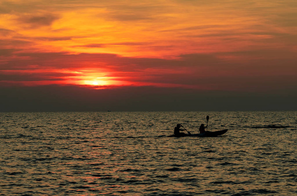 Silhouette of couple are kayaking in the sea at sunset. Kayak in the tropical sea at sunset. Romantic couple travel on summer vacation. Adventure activities of romantic couples.  Beautiful sunset sky. - Photo, Image