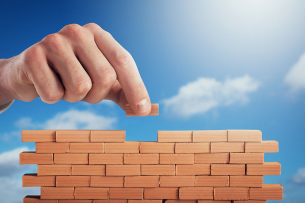 Businessman puts a brick to build a wall. Concept of new business, partnership, integration and startup - Photo, Image