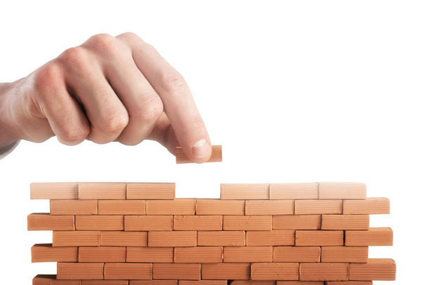 Empresário coloca um tijolo para construir uma parede. Conceito de novo negócio, parceria, integração e startup
 - Foto, Imagem
