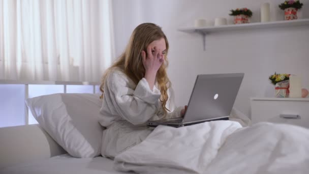 Worried girl working on laptop in bed until morning, deadline in freelance - Кадры, видео