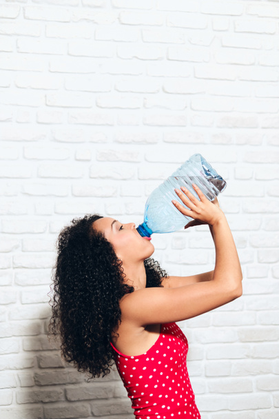 健康のためにペットボトルから水を飲むのどが渇いた若い女性 - 写真・画像