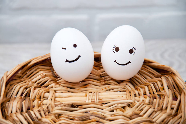 Loving couple of eggs with emoticons on a wooden basket. Congratulatory card with Easter. - Photo, Image