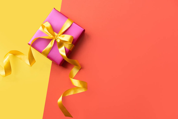 Colorful background with pink gift box. Orange and yellow background with present. Copy space - Фото, зображення