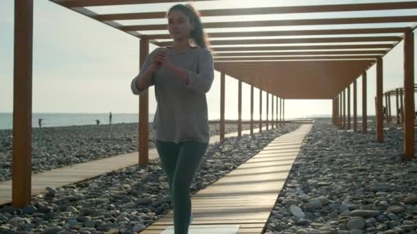 Женщина-атлет приседает на пляже в солнечный вечер, тренируясь тело
 - Кадры, видео
