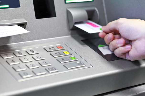 Hand inserting ATM credit card into bank machine to withdraw mon - Photo, Image